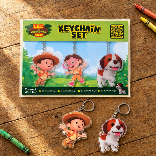 Leo The Wildlife Ranger acrylic keychain set of 3 (Leo, Katie, Hero) on a wooden table with crayons